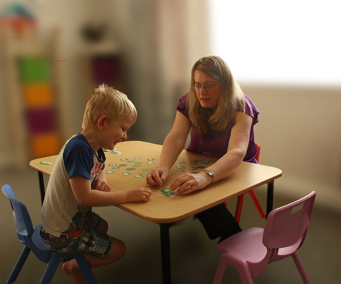 Sarah working through a table-top activity with a young child at the clinic